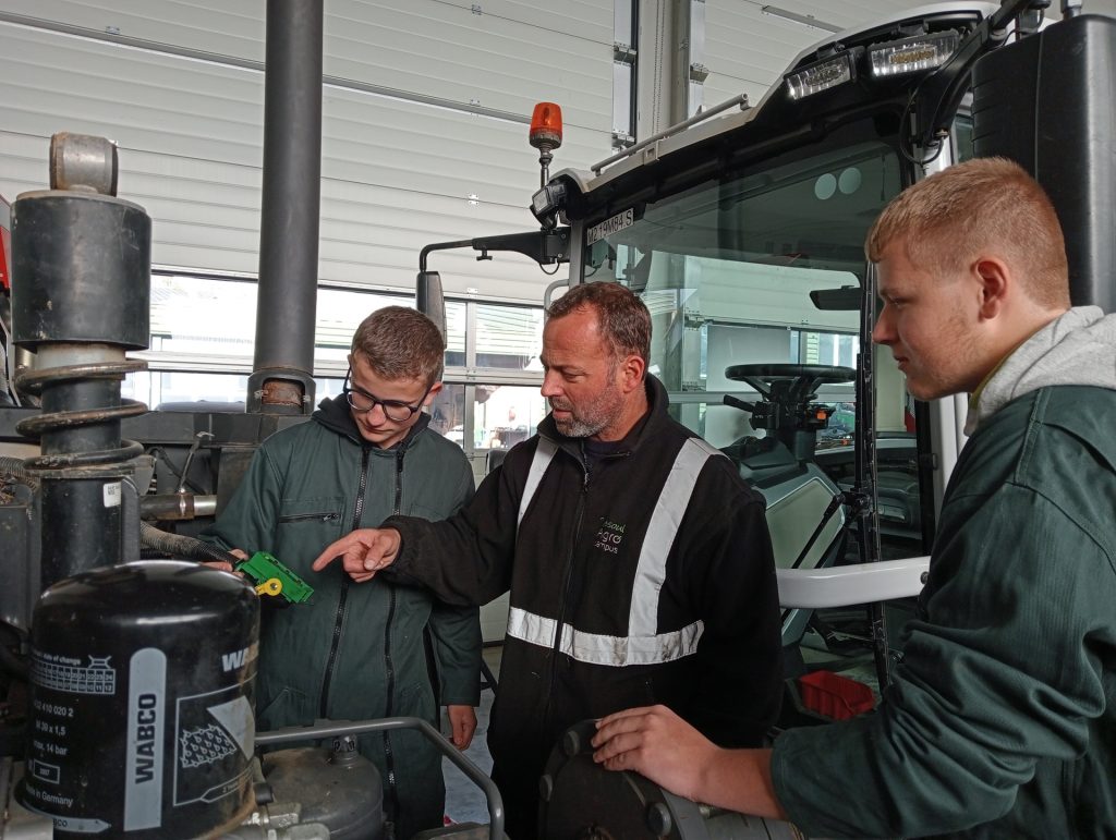 Image d'un enseignant avec ses élèves autour d'une problématique de maintenance d'engin agricole